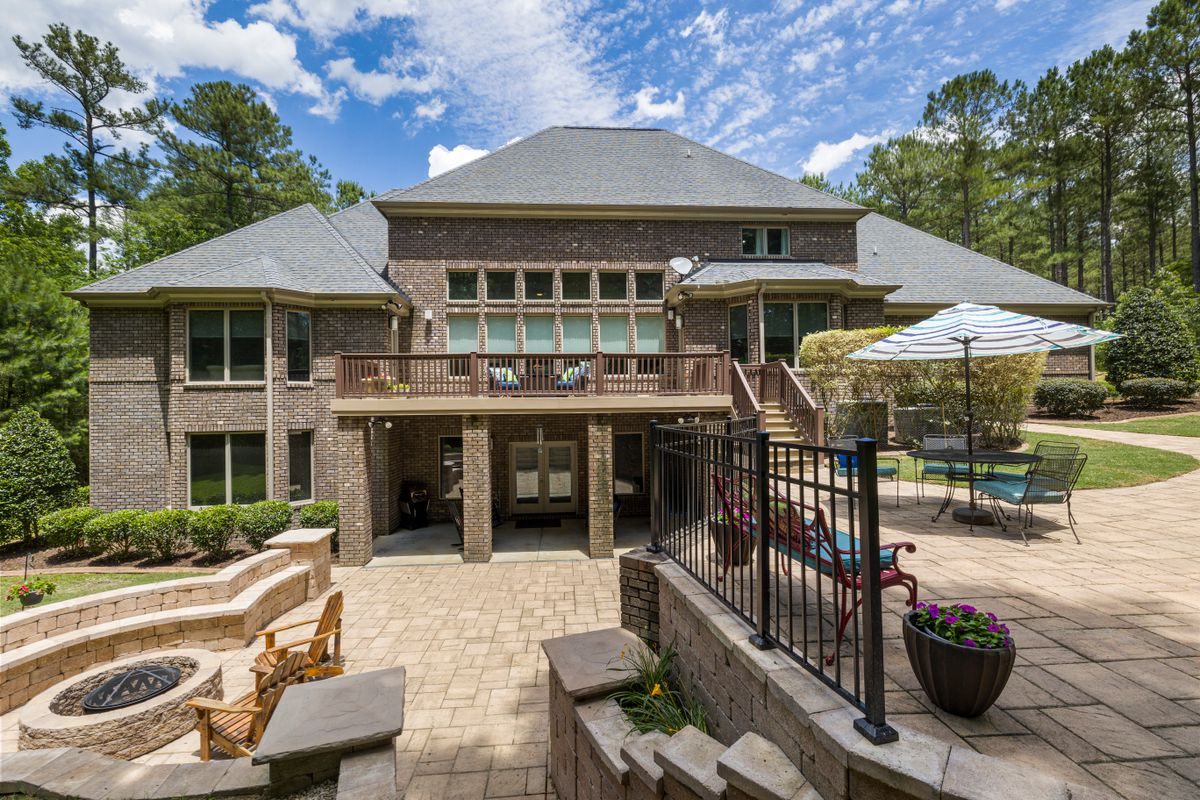 Backyard hardscape with brick home, terrace, and manicured landscaping